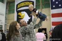 A soldier hoists his young son into the air