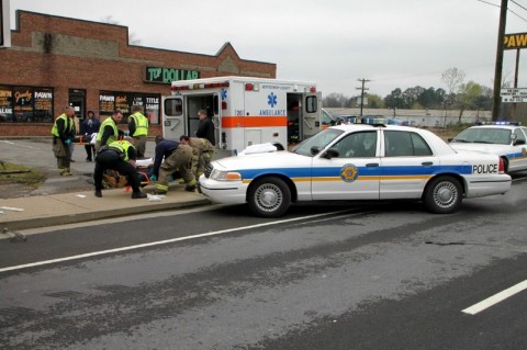 Emergency workers prepare to put an injured individual in the ambulance