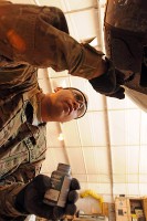 Spc. Miguel Peralta, the daytime production control representative for the airframe shop, Company B, 563rd Aviation Support Battalion touches the paint up on an OH-58 Kiowa helicopter. (Photo by Shanika Futrell)