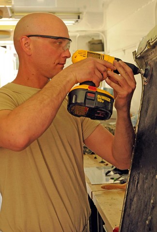 Spc. Mark Battista, a structural aviation repairer with the airframe shop for Company B, 563rd Aviation Support Battalion, conducts composite repairs on a CH-47 Chinook helicopter. (Photo by Shanika Futrell)