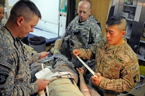 Spc. Michael Grimes and Pfc. Garry Lim, medics with the 101st Special Troops Battalion, 101st Sustainment Brigade, care for a staged injured Soldier during a mass casualty exercise, June 8th, as Col. (Dr.) Peter Napolitano, the brigade surgeon looks on. (Photo by Spc. Michael Vanpool)