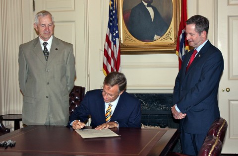 Governor Bill Haslam (center) signs Senate Bill 710 as bill sponsors State Senator Tim Barnes (right) and State Representative John Tidwell (left) look on during a signing ceremony on Wednesday, June 22nd. The bill increases restrictions against registered sex offenders entering public libraries.