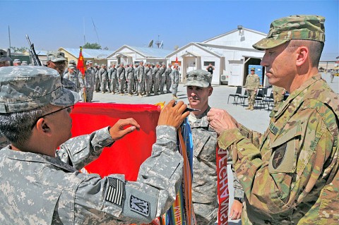 Maj. Gen. James Mallory, deputy commander, North Atlantic Treaty Organization Training Mission-Afghanistan, attaches the Meritorious Unit Commendation streamer onto the 2nd Battalion, 44th Air Defense Artillery Regiment, guidon. The battalion, originally scheduled for de-activation, was re-activated for deployment to Afghanistan as trainers to the Afghan National Army and Afghan National Police. (Sgt. 1st Class Peter Mayes/U.S. Army)