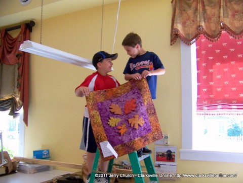 Two young boys help hang quilts as Trenton gets ready for their annual quilt show