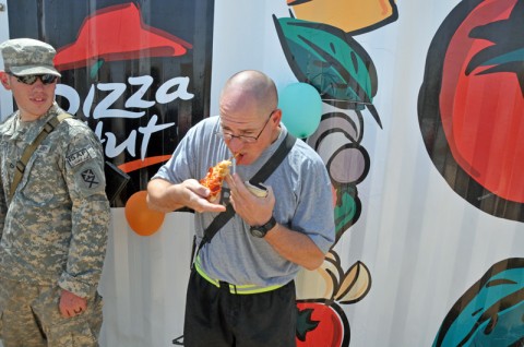 Sgt. William Paulk of the 900th Maintenance Company, Alabama National Guard, eats his first slice of Pizza Hut pepperoni pizza at the grand opening of the facility at Forward Operating Base Deh Dadi II. The Pizza Hut completes the food court on the FOB, as the 530th Combat Sustainment Support Battalion continues to expand construction projects there. (Photo by Sgt. 1st Class Peter Mayes)