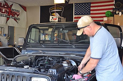 Staff Sgt. Jason Axelson, Operations NCO at the Installation Chaplain’s office, deconstructs a 1995 Jeep Wrangler YJ at his Clarksville home, July 9th. The vehicle was originally purchased by Sgt. 1st Class Charles Adkins, an 101st Sustainment Brigade Soldier, to complete as a father-son project upon his return from Afghanistan. After Adkins was killed in action, Axelson decided to complete the project in honor of the fallen Soldier and his Family. (Megan Locke, Fort Campbell Courier) Staff Sgt. Jason Axelson, Operations NCO at the Installation Chaplain’s office, deconstructs a 1995 Jeep Wrangler YJ at his Clarksville home, July 9th. The vehicle was originally purchased by Sgt. 1st Class Charles Adkins, an 101st Sustainment Brigade Soldier, to complete as a father-son project upon his return from Afghanistan. After Adkins was killed in action, Axelson decided to complete the project in honor of the fallen Soldier and his Family. (Megan Locke, Fort Campbell Courier)