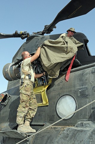 Sgt. Joshua Ommert (top), a flight engineer and Staff Sgt. Rick Carter (bottom), a flight engineer, both with Company B, 2nd Battalion, 135th Aviation Regiment, cover up an engine on a CH-47 Chinook to keep dust out while the aircraft is not in use. (Photo by Sgt. Shanika Futrell) Sgt. Joshua Ommert (top), a flight engineer and Staff Sgt. Rick Carter (bottom), a flight engineer, both with Company B, 2nd Battalion, 135th Aviation Regiment, cover up an engine on a CH-47 Chinook to keep dust out while the aircraft is not in use. (Photo by Sgt. Shanika Futrell)
