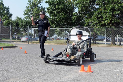 Police Lt. Raymond Lepper, a provost martial with the Directorate of Emergency Services, walks with Spc. Ian Murphy, a rifleman with Company B, 1st Battalion, 327th Infantry Regiment, 101st Airborne Division, as he gets a feel for the Simulated Impaired Driving Experience course here, Sept. 1. The SIDNE provided unique training to soldiers during Safety Stand-down Day to simulated driving under the influence while the driver was still sober. (Photo by Spc. Richard Daniels Jr.)