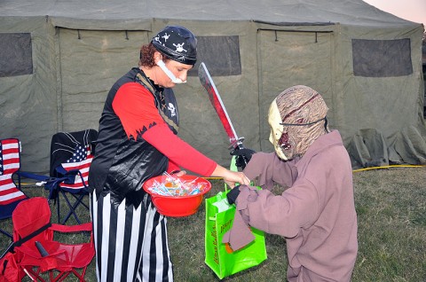 Katina Dimitro, Strike spouse of Master Sgt. Albert Dimitro of Headquarters and Headquarters Company, 2nd Brigade Combat Team, 101st Airborne Division (Air Assault), dressed as a pirate and hands out candy to the Strike family members dressed in costumes during the battalion’s Trunk or Treat event held at Strike, October 21st.