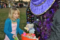 Spc. Jason Schwartz, with Headquarters and Headquarters Company, 2nd Brigade Special Troops Battalion, 2nd Brigade Combat Team, 101st Airborne Division (Air Assault), dressed in a Mardi Gras costume, hands out candy to a Strike princess and other Strike family members dressed in costumes during the battalion’s Trunk or Treat event held at Strike, October 21st.