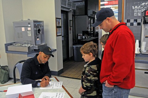 J.R. Martinez, ABC’s ‘Dancing With The Stars’ winner and former 101st Airborne Division (Air Assault) Soldier, signs personalized autographs for Sgt. Dan Horton of Headquarters and Headquarters Company, 2nd Brigade Combat Team, 101st Airborne Division (Air Assault), and Horton’s two sons David and Andrew at Fort Campbell’s Strike Dining Facility, Dec. 4th. Martinez visited his old base and unit and spoke to the Soldiers and their families about overcoming great challenges. (U.S. Army photo by Sgt. Joe Padula, 2nd BCT PAO, 101st Abn. Div.)