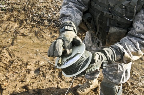 A soldier of the 1st Brigade Combat Team, 101st Airborne Division, unwinds detonations cord during demolition training here at the range Dec. 9th. (Photo by Sgt. Richard Daniels Jr.)