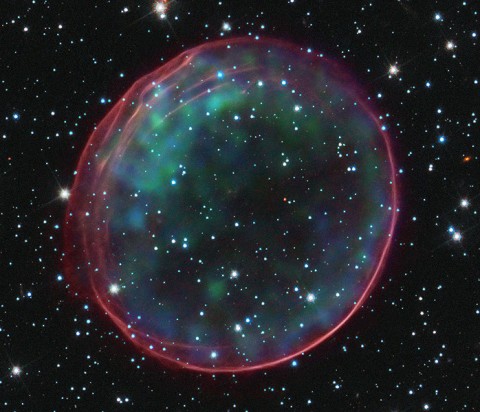 This image of Type Ia Supernova Remnant 0509-67.5 was made by combining data from two of NASA’s Great Observatories. The result shows soft green and blue hues of heated material from the X-ray data surrounded by the glowing pink optical shell, which shows the ambient gas being shocked by the expanding blast wave from the supernova. (Image Credit: NASA, ESA, CXC, SAO, the Hubble Heritage Team (STScI/AURA), J. Hughes (Rutgers University)) This image of Type Ia Supernova Remnant 0509-67.5 was made by combining data from two of NASA’s Great Observatories. The result shows soft green and blue hues of heated material from the X-ray data surrounded by the glowing pink optical shell, which shows the ambient gas being shocked by the expanding blast wave from the supernova. (Image Credit: NASA, ESA, CXC, SAO, the Hubble Heritage Team (STScI/AURA), J. Hughes (Rutgers University))