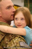 A soldier's eyes water up as he holds his daughter for the first time in a year