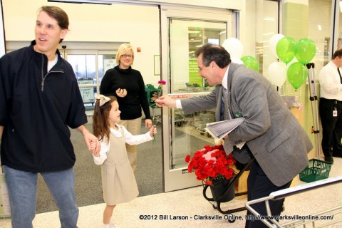 Store manager Norman Rubio Jr. gives a young patron a flower as she enters the store during the grand opening of the Publix store.