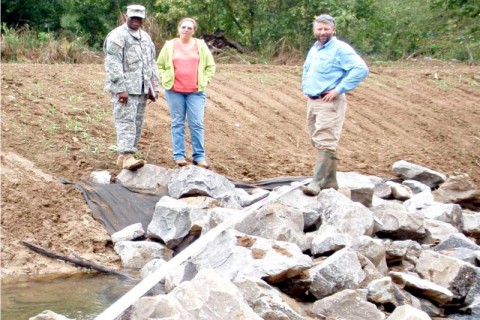 Earth Team Volunteer Sgt. Patrick Bower, Soil Conservationist Janet Coleman and District Conservationist Kevin Hart inspect a streambank protection jetty.