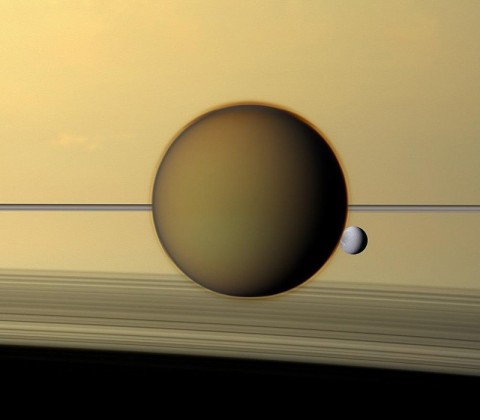 Saturn's third-largest moon Dione can be seen through the haze of its largest moon, Titan, in this view of the two posing before the planet and its rings from NASA's Cassini spacecraft. (Image credit: NASA/JPL-Caltech/SSI)