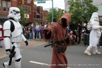 A Tusken Raider from Star Wars is escorted by Storm Troopers