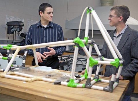 APSU physics students Elijah Jensen and John Walker discuss the half-scale prototype race car frame they designed and built. The next step is to build the full-scale formula SAE racecar. (Photo by Amber Fair/APSU).