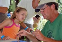 Brainard Palmer-Ball, Jr. bands a hummingbird as a young visitor watches.