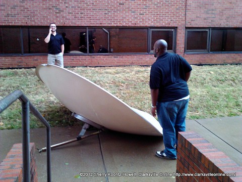 Christian Hodge (front) and Joe Mendes (rear) inspect the satellite dish blown off the Music and Mass Communication Building in yesterday's Storm. They are Graduate Assistants in the Communication Department. 