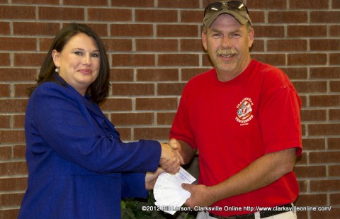 Amy Carroll of Big Brothers, Big Sisters of Clarksville receiving 70 Tickets to a fundraising concert featuring John Michael Montgomery from  David Kirkland, the president of Clarksville Firefighters Local 3180 