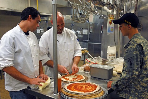 The Blackhorse Pub and Brewery chefs Brandon Crotzer and Zachary Matthews give tips on cooking pizza "Blackhorse Style" to Oasis Dining Facility cook Pfc. Robert Archuleta. (5th Special Forces Group (Airborne) Public Affairs)