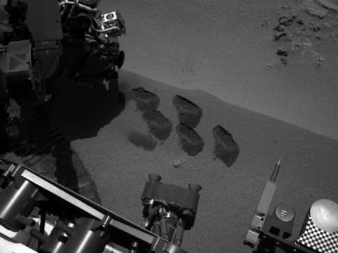 NASA's Mars rover Curiosity used a mechanism on its robotic arm to dig up five scoopfuls of material from a patch of dusty sand called "Rocknest," producing the five bite-mark pits visible in this image from the rover's left Navigation Camera (Navcam). Each of the pits is about 2 inches (5 centimeters) wide. (Image credit: NASA/JPL-Caltech)