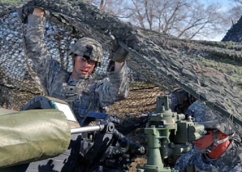 Spc. Ricky Pearson lifts camouflage netting to keep it above the head of Staff Sgt. Tyler Chatfield during the 101st Airborne Division Top Gun competition, held Nov. 14-15, at Fort Campbell. Pearson and Chatfield serve as crewmembers of an M-119 Howitzer with Bravo Battery, 1st Battalion, 320th Field Artillery Regiment, 2nd Brigade Combat Team, 101st. (Photo by Sgt. David Hodge, 101st Airborne Division Public Affairs)