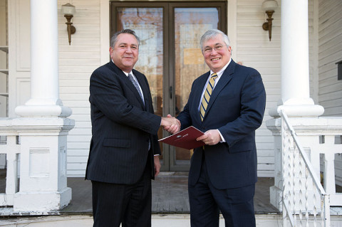 Heritage Bank President Keith Bennett (left) shakes hands with APSU President Tim Hall on December 11th after presenting the deed to the house behind them, located at 1220 Madison Street. APSU plans to sell the property, with the proceeds going toward the Governors Stadium renovation project. (Photo by Beth Liggett, APSU photographer)