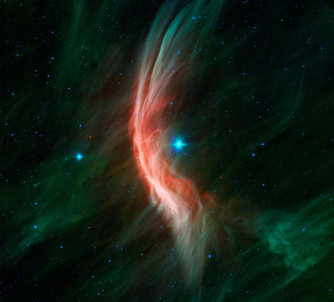 The giant star Zeta Ophiuchi is having a "shocking" effect on the surrounding dust clouds in this infrared image from NASA's Spitzer Space Telescope. Stellar winds flowing out from this fast-moving star are making ripples in the dust as it approaches, creating a bow shock seen as glowing gossamer threads, which, for this star, are only seen in infrared light. (Image credit: NASA/JPL-Caltech)