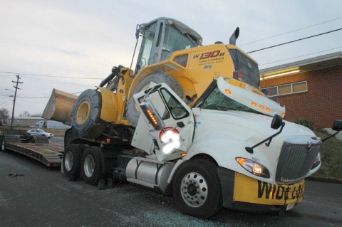 Front end loader shifts on flatbed trailer coming to rest on the cab of the truck trapping the driver inside. (Photo by CPD-Jim Knoll)