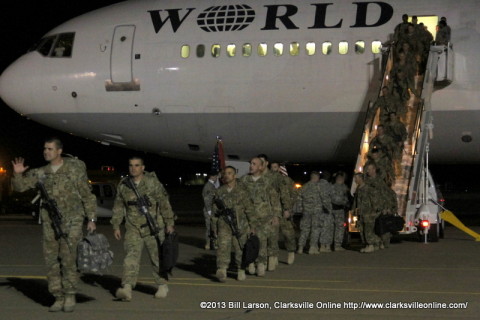 The returning soldiers disembark from the aircraft and head past their families to the hanger