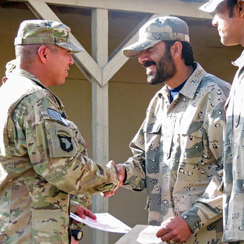 Army Sgt. Luciano Mada, a medic assigned to Headquarters, Headquarters Company, 3rd Battalion, 187th Infantry Regiment, 3rd Brigade Combat Team “Rakkasans,” 101st Airborne Division (Air Assault), shakes hands with an Afghan Border Policeman during their graduation ceremony of his medical course at Forward Operating Base Salerno, Afghanistan. (Courtesy Photo)