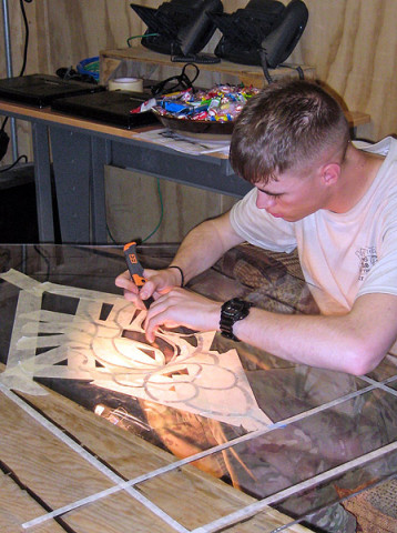 U.S. Army Spc. Brandon Corbin, chaplain’s assistant, 626 Brigade Support Battalion, 3rd Brigade Combat Team “Rakkasans, 101st Airborne Division (Air Assault), carefully cuts masking tape away from plexiglass before painting the windows that will be hung in the chapel on Forward Operating Base Salerno, Afghanistan. A team of chaplain’s assistants teamed up together to finish the restoration of their chapel after it badly damaged by an attack on the FOB in the summer of 2012.  (Courtesy photo provided by Spc. Erika Espeseth, chaplain’s assistant, 3rd Special Troops Battalion)