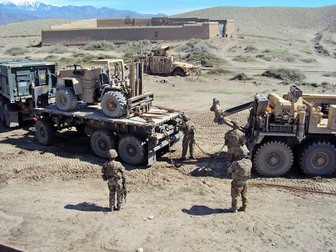 U.S. Army Soldiers, Sgt. James Kendall and Spc. Peter Brousseau, 426th Brigade Support Battalion, 1st Brigade Combat Team, 101st Airborne Division (Air Assault), attach chains to the back of an M1120 HEMTT Load Handling System in order to recover the vehicle from a sinkhole. (U.S. Army photo by 1st Lt. Lisa Maginot, 426th BSB Unit Public Affairs Representative)