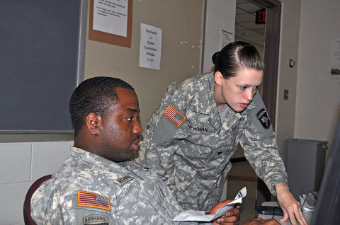 Spc. Miriah Newman (right) a signal support noncommissioned officer with Headquarters, Headquarters Battalion, 101st Airborne Division, and Sgt. Lavon Richardson, human resources noncommissioned officer with 2nd Battalion, 327th Infantry Regiment, 1st Brigade Combat Team, 101st Airborne Division, check the computers prior to the high school graduation to make sure they’re working properly as part of the “Operation Yellow Ribbon” program. (Photo by Master Sgt. Pete Mayes)