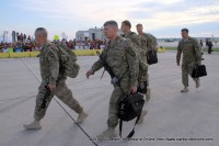 Soldiers walk past their families after disembarking from the airplane