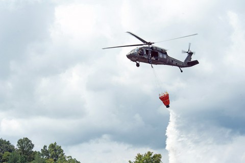 A UH-60 Black Hawk helicopter with A Company, 6th Battalion, 101st Combat Aviation Brigade, 101st Airborne Division (Air Assault), dumps water out of a bucket slung from the helicopter during wildfire operations training at Fort Campbell, Ky., Aug. 19, 2013. (U.S. Army photo by Sgt. Duncan Brennan, 101st CAB Public Affairs)