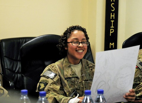 U.S. Army Pvt. Alice M. Harris, a human resource specialist with the Headquarters and Headquarters Battalion, 101st Airborne Division (Air Assault), looks a her caricature drawn by MAD Magazine cartoonist Tom Richmond at Kandahar Airfield, in Parwan Province, Afghanistan, Sept. 6, 2013. Eight nationally recognized members of the National Cartoonists Society were part of a USO tour in Afghanistan. (U.S. Army photo by Sgt. Sinthia Rosario/Released)