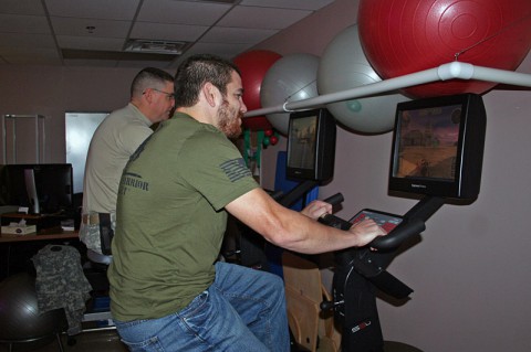 Ultimate Fighting Championship guest fighter Jim Miller rides a stationary bike on a simulated course with Sgt. 1st Class Landon Ranker Nov. 4. 2013 at the Warrior Resiliency and Recovery Center on Fort Campbell, Ky. Ranker received treatment for a traumatic brain injury at the center and now serves as a cadre member within Fort Campbell's Warrior Transition Battalion. Miller, along with fellow UFC guest fighters Chuck Liddell, Forrest Griffin and Fredson Paixao, received a hands-on tour through portions of TBI therapy sessions that Soldiers receive at the center, which will soon become a National Intrepid Center of Excellence satellite site, known as the Intrepid Spirit. (U.S. Army Photo by Laura Boyd)