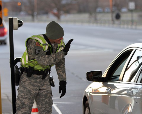 Spc. Bryan Clark, an infantryman from 1st Battalion, 187th Infantry Regiment, 3rd Brigade, 101st Airborne Division (Air Assault), sends a vehicle on its way with a friendly wave Dec. 12, at Fort Campbell. Clark is one of 72 soldiers from the division who recently assumed the bulk of Fort Campbell's access control point mission. (U.S. Army photo by Sgt. Leejay Lockhart, 101st Sustainment Brigade Public Affairs)