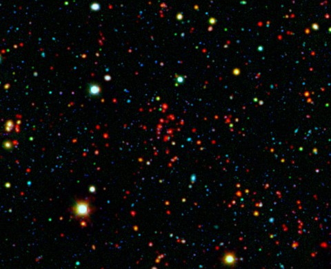 The collection of red dots seen near the center of this image show one of several very distant galaxy clusters discovered by combining ground-based optical data from the National Optical Astronomy Observatory's Kitt Peak National Observatory with infrared data from NASA's Spitzer Space Telescope. This galaxy cluster, named ISCS J1434.7+3519, is located about 9 billion light-years from Earth. (NASA/JPL-Caltech/KPNO/University of Missouri-Kansas City) The collection of red dots seen near the center of this image show one of several very distant galaxy clusters discovered by combining ground-based optical data from the National Optical Astronomy Observatory's Kitt Peak National Observatory with infrared data from NASA's Spitzer Space Telescope. This galaxy cluster, named ISCS J1434.7+3519, is located about 9 billion light-years from Earth. (NASA/JPL-Caltech/KPNO/University of Missouri-Kansas City)