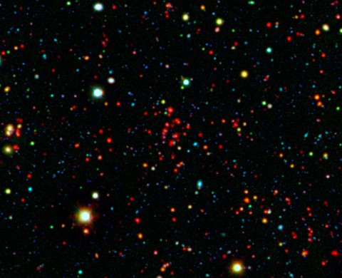 The collection of red dots seen near the center of this image show one of several very distant galaxy clusters discovered by combining ground-based optical data from the National Optical Astronomy Observatory's Kitt Peak National Observatory with infrared data from NASA's Spitzer Space Telescope. This galaxy cluster, named ISCS J1434.7+3519, is located about 9 billion light-years from Earth. (NASA/JPL-Caltech/KPNO/University of Missouri-Kansas City)