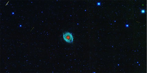 A dying star, called the Helix nebula, is shown surrounded by the tracks of asteroids in an image captured by NASA's Wide-field Infrared Survey Explorer, or WISE. (NASA/JPL-Caltech/UCLA)