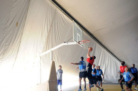 Pfc. Ryan M. Sindle, a native of Elkhart, IN, and convoy security team driver for Task Force Lifeliner, jumps up to shoot the basketball towards the hoop during a game between officers and enlisted soldiers, Jan. 5, 2014, at Bagram Air Field, Parwan province, Afghanistan. During the game the officers wore blue jerseys and the enlisted wore red jerseys. (Sgt. Sinthia Rosario, Task Force Lifeliners Public Affairs)