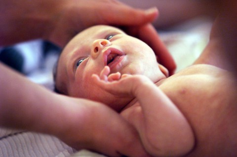 A newborn baby gets caressed by its new mother