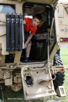 A boy peeks out the back of an APC