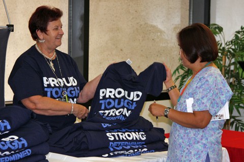 Sherry Fanara, provider resiliency trainer and licensed professional counselor for Blanchfield Army Community Hospital hands a PTSD Awareness shirt to Angie Summers, a registered nurse in BACH’s Same Day Surgery June 25, 2014 to help promote PTSD awareness. BACH staff members are encouraged to wear their t-shirts on National PTSD Awareness Day Friday, June 27. (U.S Army photo by Stacy Rzepka)