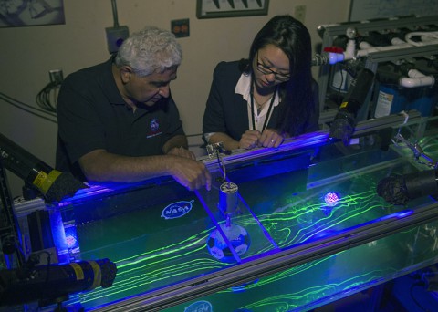 Dr. Rabi Mehta and Christina Ngo view a test of a of a traditional 32-panel football scale-model in the 17-inch water channel. Flow patterns are visualized using florescent dye and black lights. (NASA's Ames Research Center)